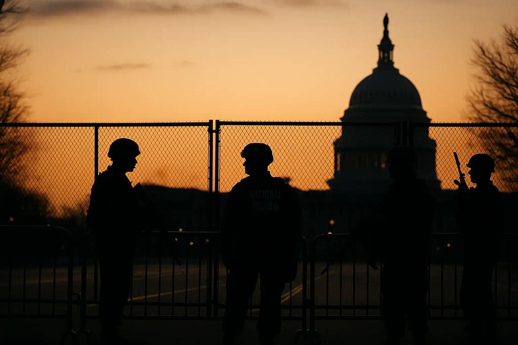 Silhouetted National Guard members near security barriers in Washington, D.C.
